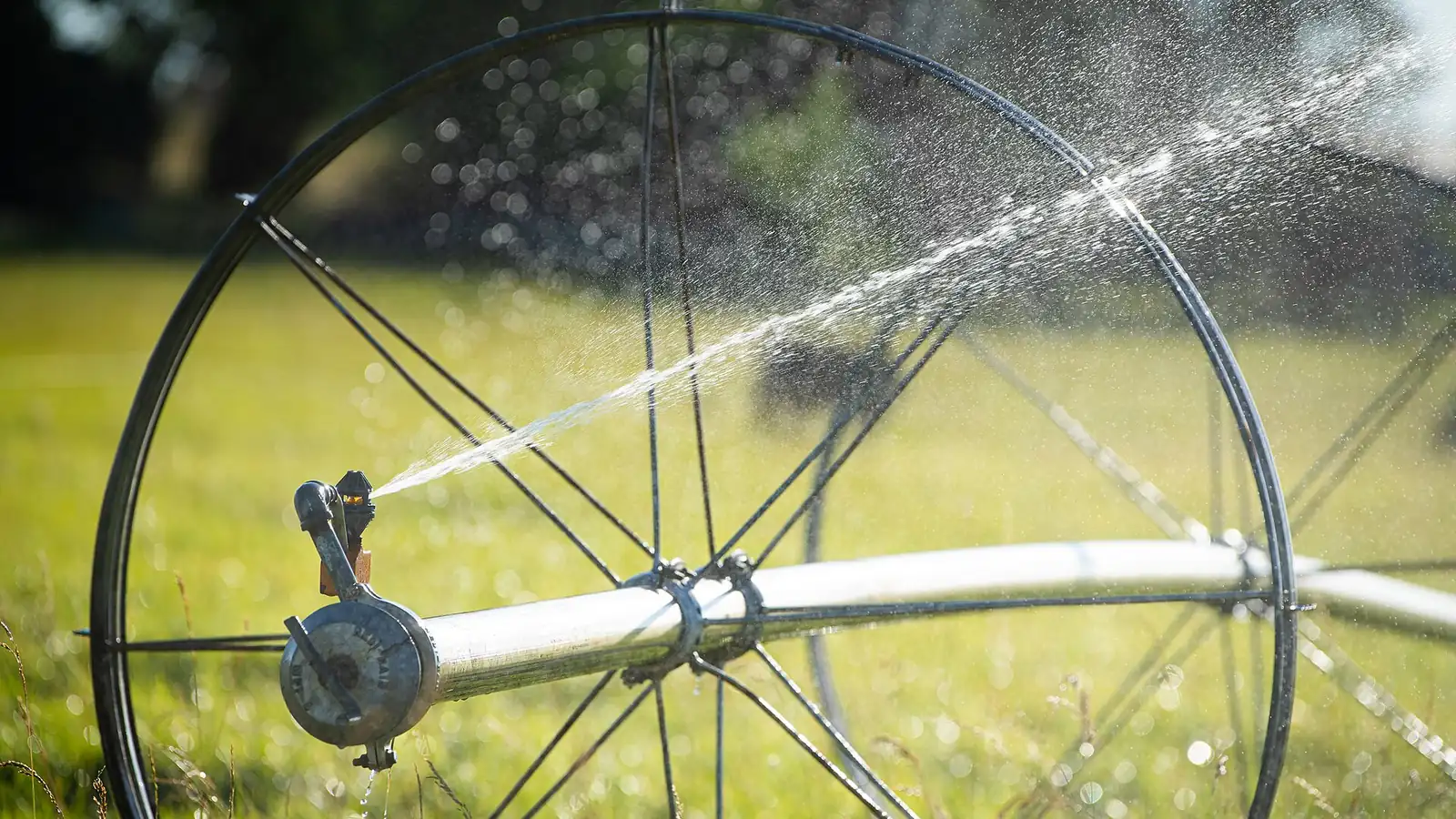 Wheeled sprinkler gun spraying on bare ground