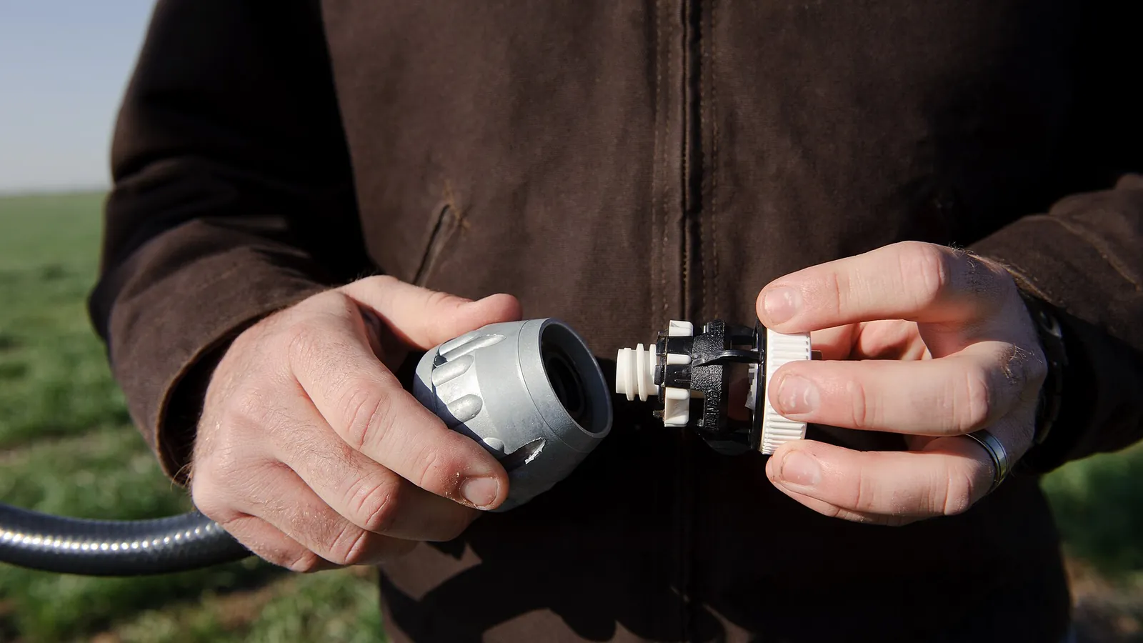 Hands connecting a hose quick-coupling on an irrigation line