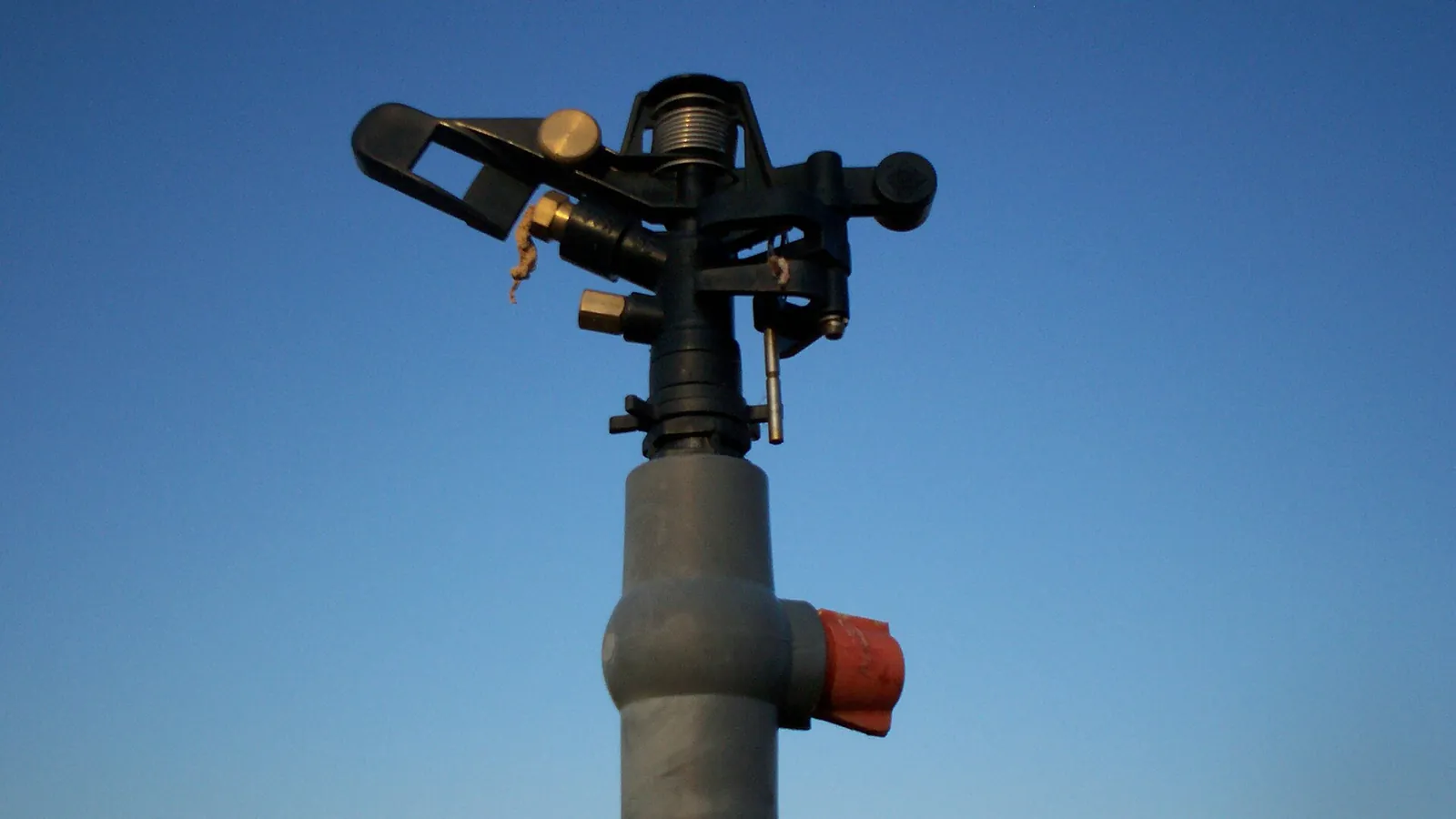 Impact sprinkler against clear blue sky