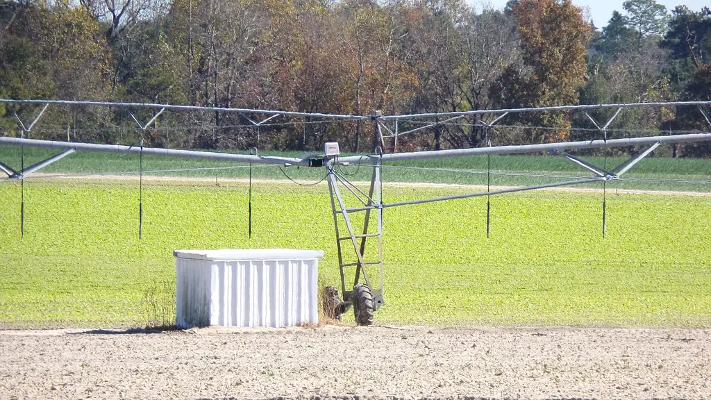 Center pivot sprinkler span over young field with pump house